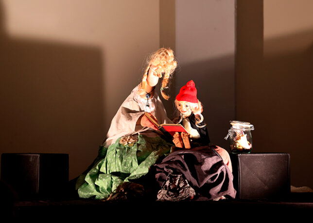 Fußtheater auf kleiner Bühne: zwei beleuchtete Puppen im Scheinwerferlicht.