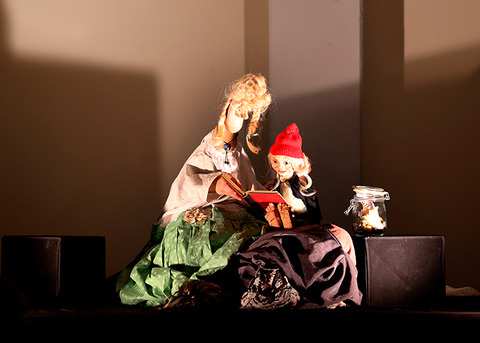 Fußtheater auf kleiner Bühne: zwei beleuchtete Puppen im Scheinwerferlicht.