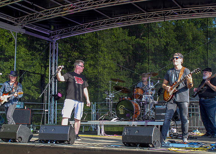 ThinkLizzy auf einer Bühne im Hintergrund ist ein Wald zu sehen