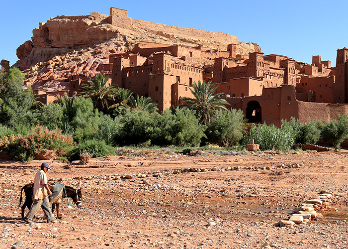 Ein Stadt in Marokko davor ist ein Esel und ein Mann zu sehen